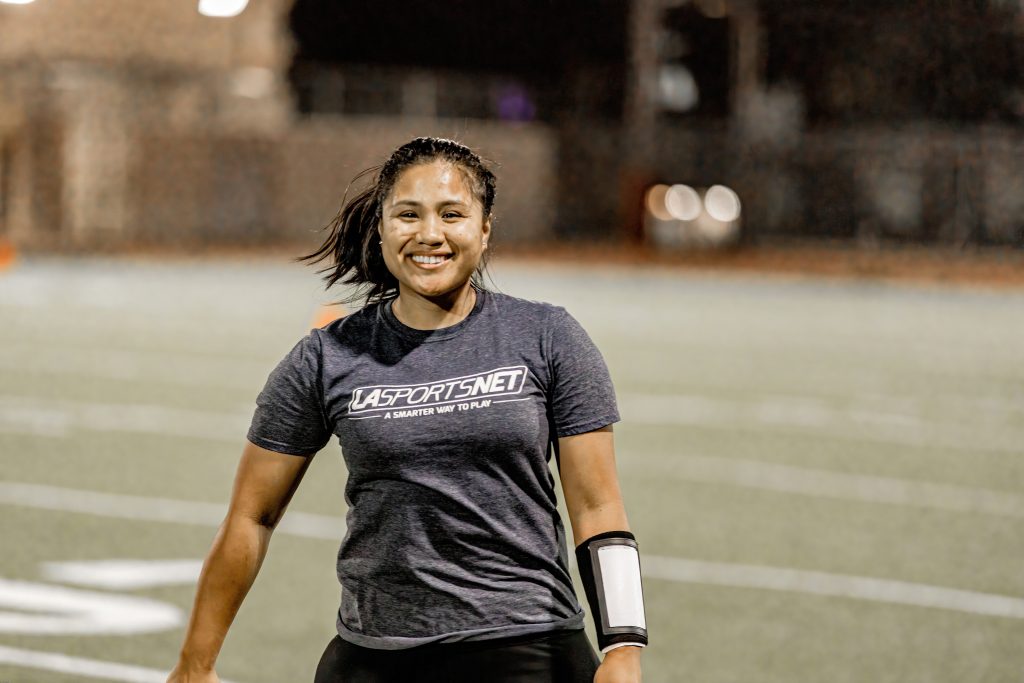 girl smiling at the camera during a sport league game