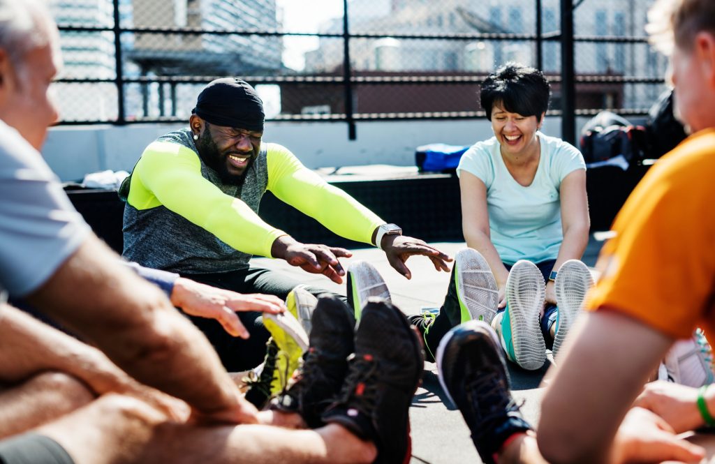 A group of people actively exercising and working out inside a modern fitness gym, highlighting a great way to get in shape playing sports and staying active.